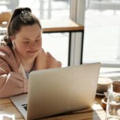 young girl using a laptop while having breakfast